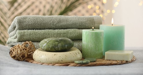 Photo of Spa composition. Burning candles, stones, soap and towels on soft grey surface