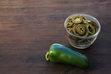 Fresh and pickled green jalapeno peppers on wooden table. Space for text