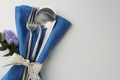 Photo of Stylish setting with cutlery and napkin on white textured table, top view. Space for text