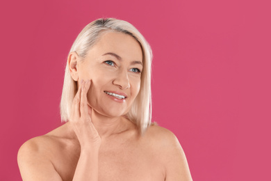 Portrait of beautiful mature woman on pink background. Space for text
