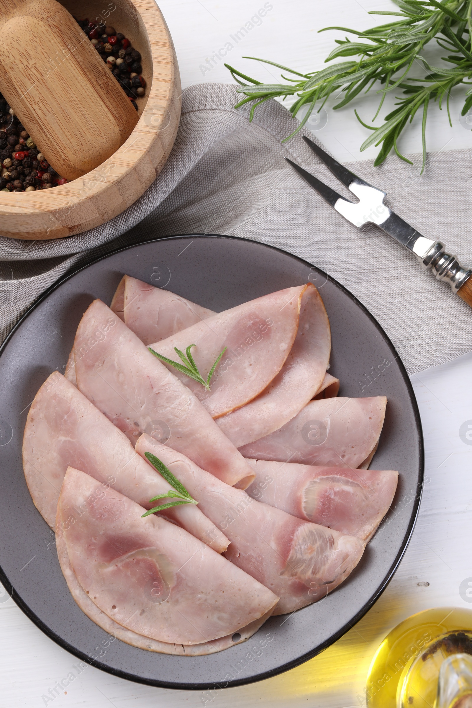 Photo of Tasty ham with rosemary served on white table, flat lay