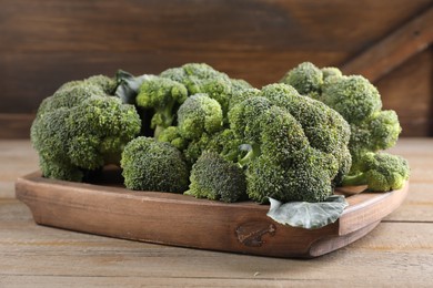 Tray with fresh raw broccoli on wooden table, closeup