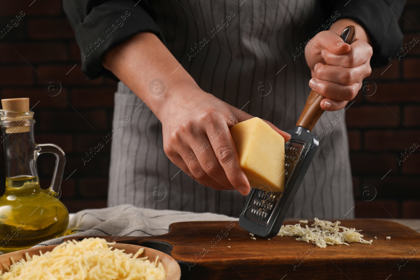 Photo of Woman grating cheese at wooden table, closeup