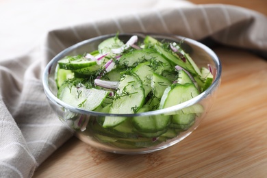 Photo of Bowl of tasty cucumber salad served on wooden table