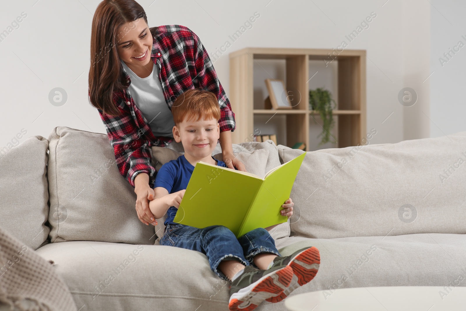 Photo of Happy mother reading book with her child at home, space for text