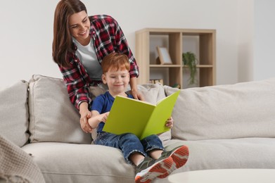 Photo of Happy mother reading book with her child at home, space for text