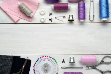 Photo of Flat lay composition with thimbles and different sewing tools on white wooden table. Space for text
