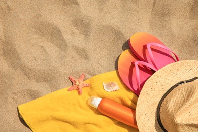 Photo of Straw hat, flip flops and other beach items on sand, flat lay. Space for text
