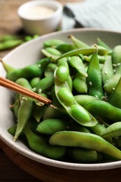 Photo of Green edamame beans in pods served on wooden table, closeup