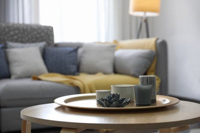 Wooden table with candles and tray in living room. Interior design