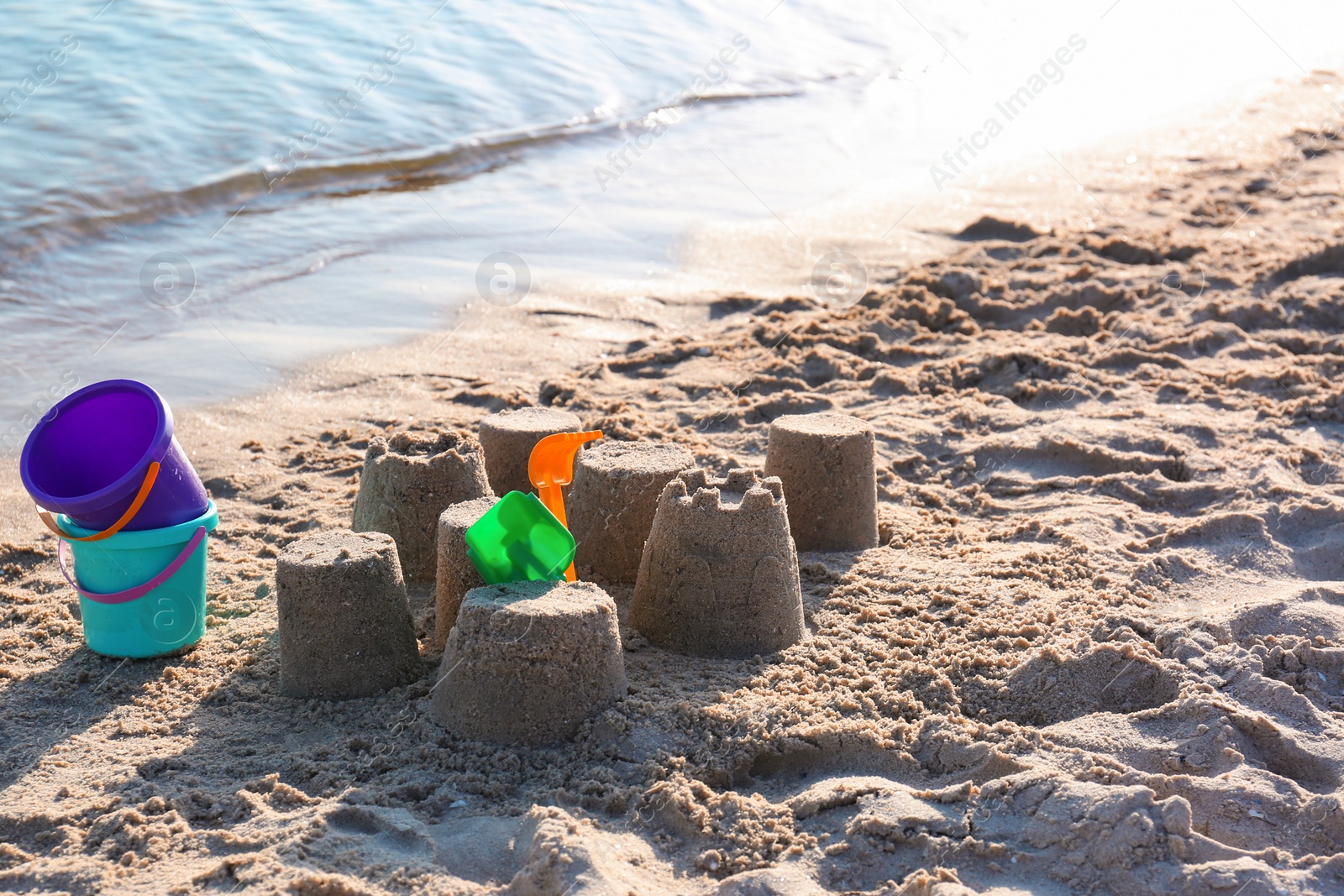 Photo of Little sand figures and plastic toys on beach near sea. Space for text