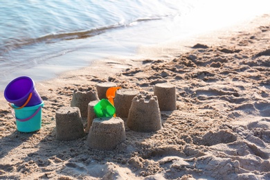 Photo of Little sand figures and plastic toys on beach near sea. Space for text