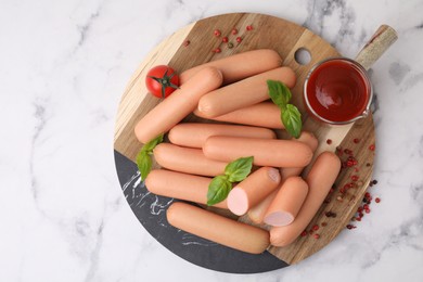 Delicious boiled sausages with spices, sauce and tomato on white marble table, top view