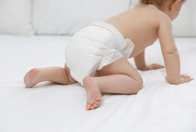 Photo of Cute little baby in diaper on bed, closeup