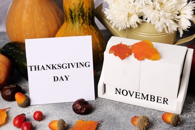 Thanksgiving day, holiday celebrated every fourth Thursday in November. Autumn composition with wooden block calendar and paper card on grey table