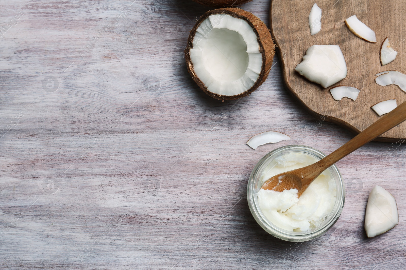 Photo of Jar with coconut oil and nut pieces on wooden background