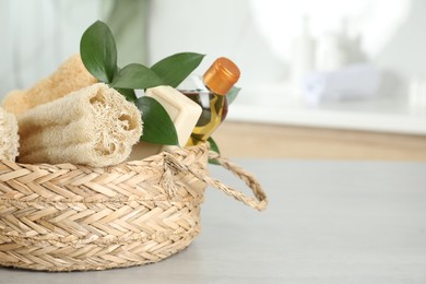 Photo of Natural loofah sponges in wicker basket on table indoors, closeup. Space for text