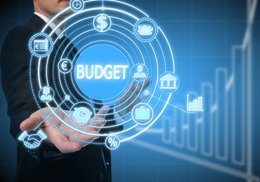 Image of Budget management. Businessman demonstrating virtual scheme with different financial icons on blue background, closeup