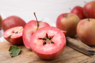 Tasty apples with red pulp and knife on wooden board, closeup