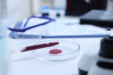 Photo of Dripping blood sample onto Petri dish on white table in laboratory, closeup