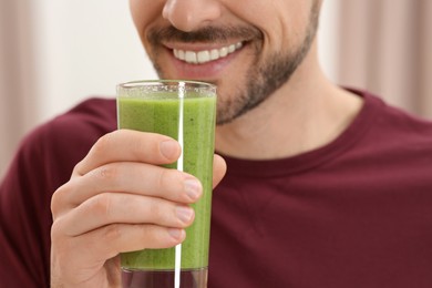 Photo of Happy man drinking delicious fresh smoothie indoors, closeup