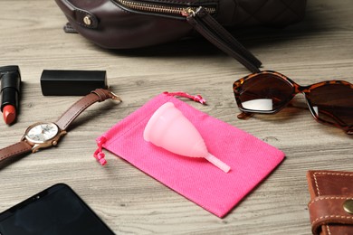 Photo of Menstrual cup and different women's accessories on wooden table
