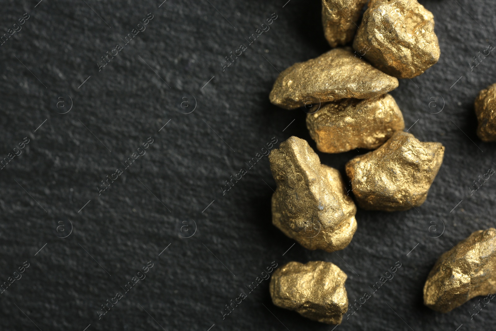 Photo of Shiny gold nuggets on grey textured surface, flat lay. Space for text
