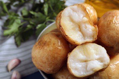 Photo of Bowl of tasty whole baked potatoes, closeup view
