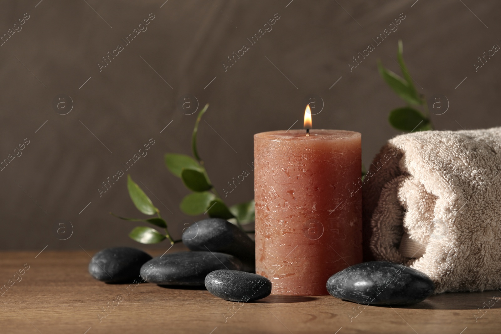 Photo of Composition with candle and spa stones on wooden table. Space for text