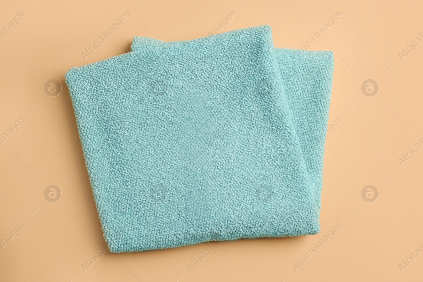 Photo of Clean soft folded towel on pale orange background, top view