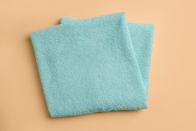 Photo of Clean soft folded towel on pale orange background, top view