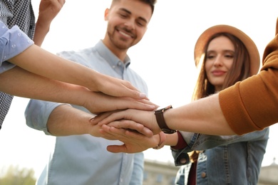 Photo of Happy young people holding hands together outdoors on sunny day, closeup