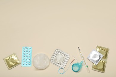Photo of Contraceptive pills, condoms, intrauterine device and thermometer on beige background, flat lay with space for text. Choice of birth control method