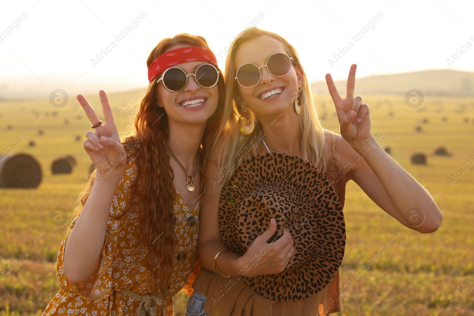 Photo of Beautiful happy hippie women showing peace signs in field