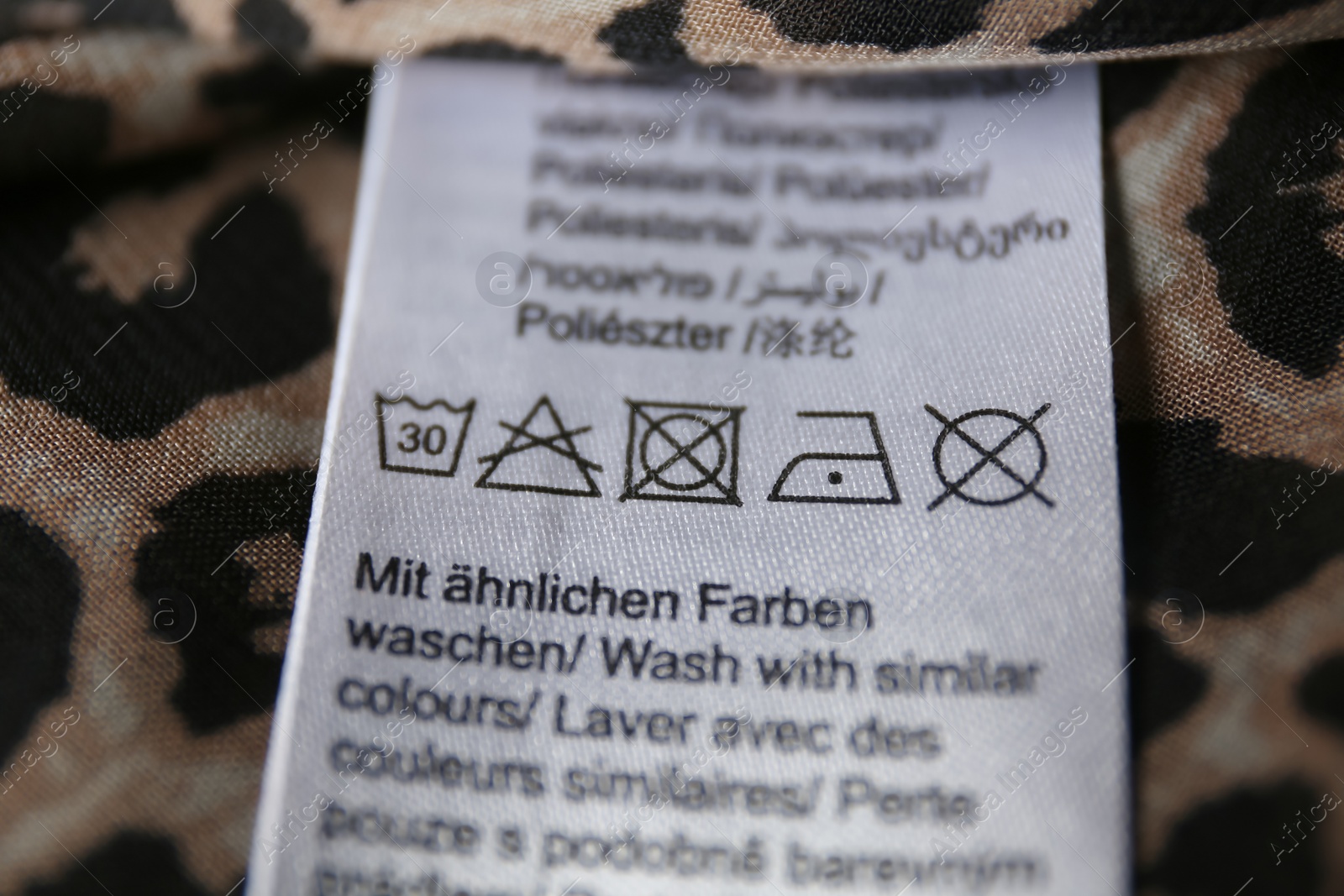 Photo of Clothing label with care symbols on shirt, closeup view
