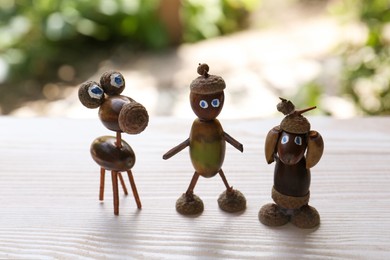 Cute figures made of acorns on white wooden table