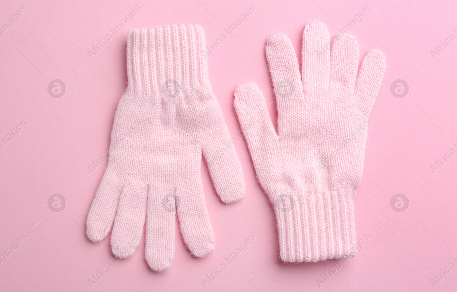Photo of Pair of stylish woolen gloves on pink background, flat lay