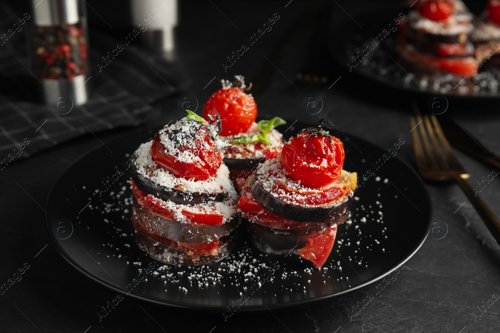 Photo of Baked eggplant with tomatoes, cheese and basil on black table