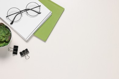 Glasses and different stationery on white desk, flat lay with space for text. Home office