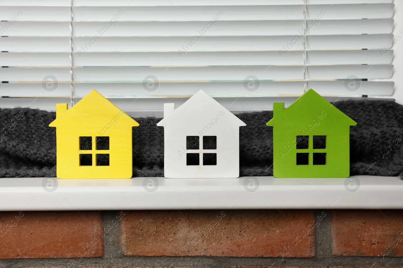 Photo of Different house models on windowsill indoors. Heating efficiency