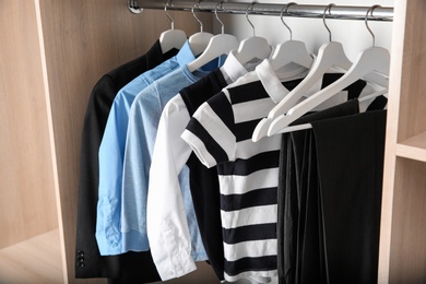 Wardrobe with stylish boy's clothes hanging on rack