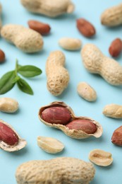 Photo of Fresh peanuts and leaves on light blue table, above view