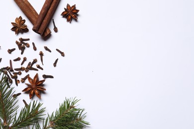 Different spices and fir branches on white table, flat lay. Space for text