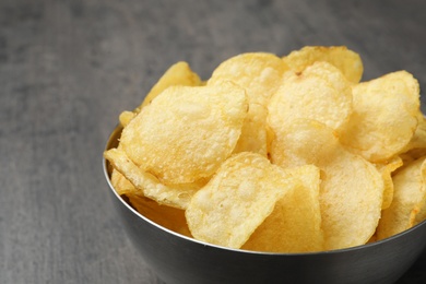 Delicious crispy potato chips in bowl on table, closeup