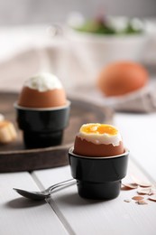 Photo of Fresh soft boiled egg in cup served on white wooden table