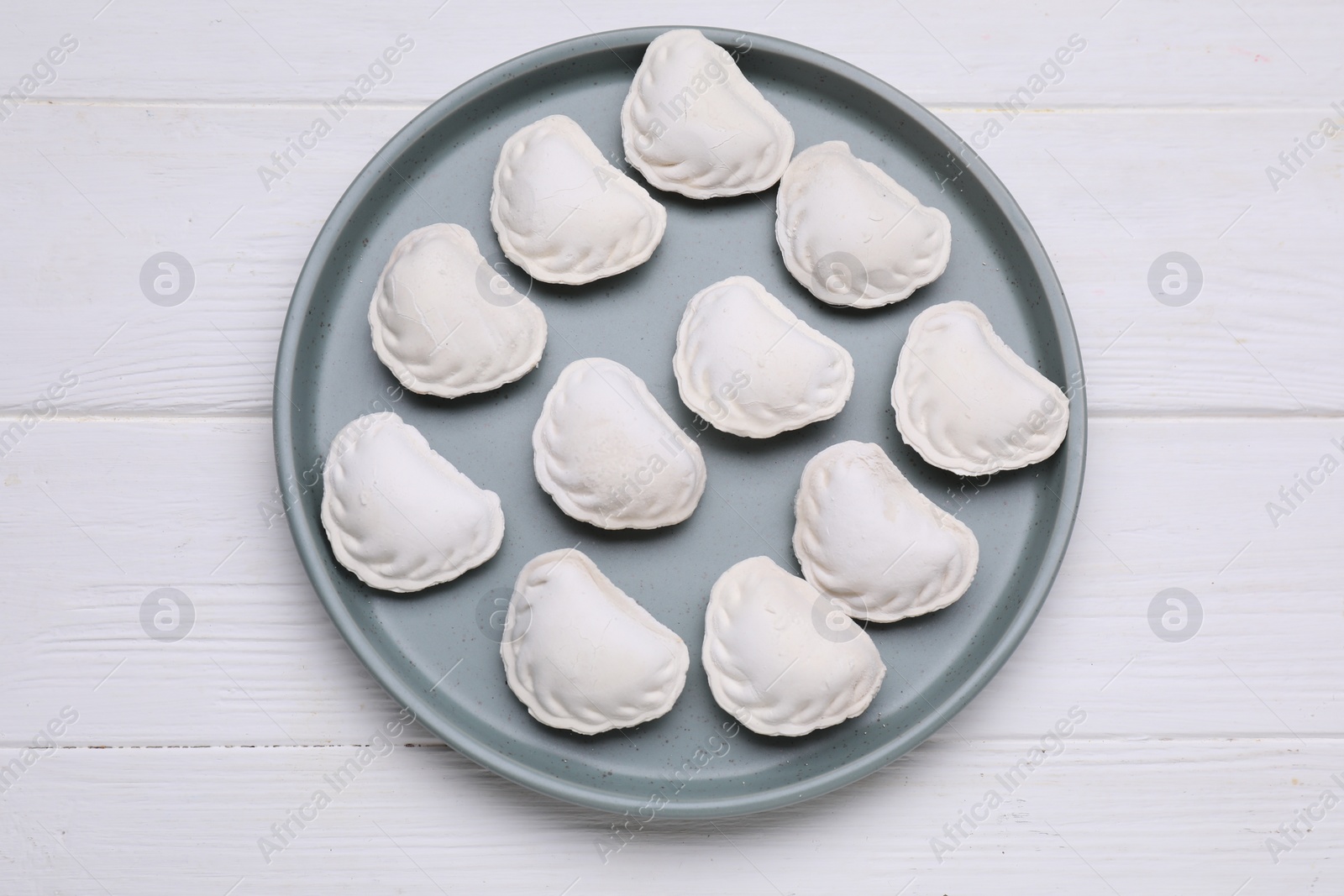 Photo of Raw dumplings (varenyky) on white wooden table, top view