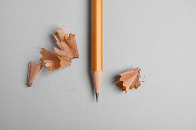 Pencil and shavings on grey background, top view