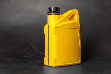 Photo of Motor oil in yellow canister on black background