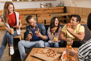 Group of friends having fun party with delicious pizza in cafe