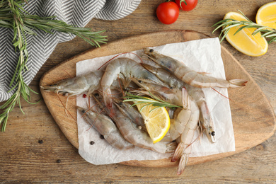 Photo of Flat lay composition with raw shrimps on wooden table